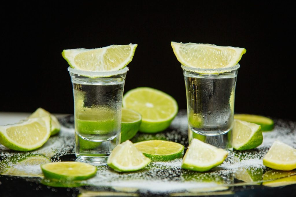 two shots of tequila with sliced lemon on top